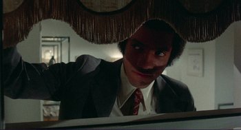 Movie still from “Sisters” (1972), directed by Brian De Palma – A man in a suit and tie looking into a mirror; Medium shot, Low angle