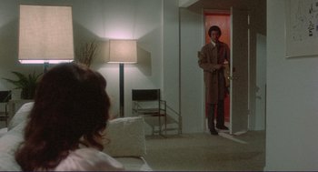 Movie still from “Sisters” (1972), directed by Brian De Palma – A man standing in front of a door in a living room; Wide shot, Over the shoulder angle
