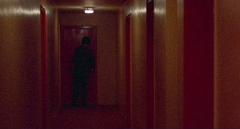 Movie still from “Sisters” (1972), directed by Brian De Palma – A man standing in a hallway in front of a door; Extreme Wide shot, High angle