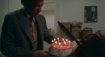 Movie still from “Sisters” (1972), directed by Brian De Palma – A man cutting a cake with a large knife; Medium shot, High angle