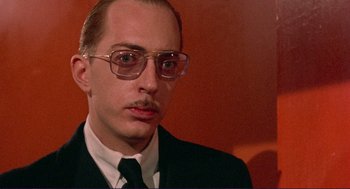 Movie still from “Sisters” (1972), directed by Brian De Palma – A person wearing glasses and a suit; Close Up shot, Low angle