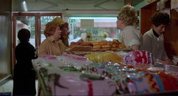 Movie still from “Sisters” (1972), directed by Brian De Palma – A group of people sitting at a table with food on top of it; Wide shot, Over the shoulder angle