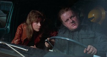 Movie still from “Sisters” (1972), directed by Brian De Palma – A man and a woman looking at a cell phone in a car; Close Up shot, Over the shoulder angle