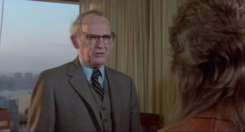 Movie still from “Sisters” (1972), directed by Brian De Palma – An older man wearing a suit and tie talking to an older woman; Close Up shot, Over the shoulder angle