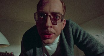 Movie still from “Sisters” (1972), directed by Brian De Palma – A person wearing glasses and a sweater; Close Up shot, Low angle