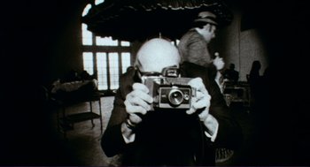 Movie still from “Sisters” (1972), directed by Brian De Palma – An older man taking a picture of himself with a camera; Extreme Close Up shot, Low angle