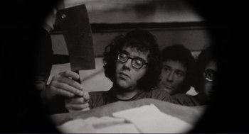 Movie still from “Sisters” (1972), directed by Brian De Palma – A man holding a meat cleaver while sitting next to another man; Close Up shot, Low angle