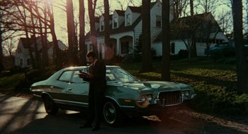 Movie still from “Sisters” (1972), directed by Brian De Palma – A man standing in front of a car in a driveway; Wide shot, Low angle