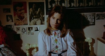 Movie still from “Sisters” (1972), directed by Brian De Palma – A woman in a white dress sitting in front of pictures; Close Up shot, Low angle
