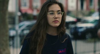 Movie still from “Skate Kitchen” (2018), directed by Crystal Moselle – A woman with long brown hair wearing glasses; Close Up shot, Low angle
