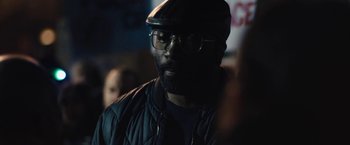 Movie still from “Skin” (2018), directed by Guy Nattiv – A person wearing glasses and a hat; Close Up shot, Over the shoulder angle
