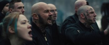 Movie still from “Skin” (2018), directed by Guy Nattiv – A man with a bald head is yelling; Medium shot, Over the shoulder angle