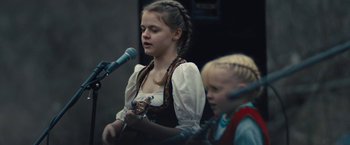 Movie still from “Skin” (2018), directed by Guy Nattiv – Two young girls are singing into microphones in front of a microphone; Close Up shot, Over the shoulder angle
