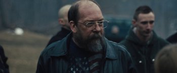 Movie still from “Skin” (2018), directed by Guy Nattiv – A man with a bald head and a beard wearing glasses; Close Up shot, Over the shoulder angle
