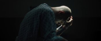 Movie still from “Skin” (2018), directed by Guy Nattiv – A man with a shaved head is praying; Close Up shot, Low angle