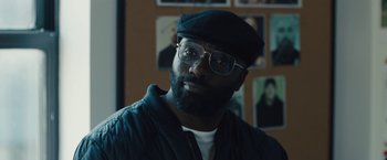 Movie still from “Skin” (2018), directed by Guy Nattiv – A man with a beard wearing glasses and a hat; Close Up shot, Over the shoulder angle