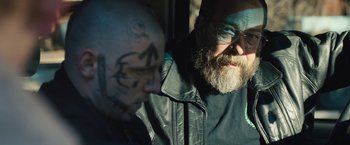 Movie still from “Skin” (2018), directed by Guy Nattiv – A man in a leather jacket with a beard and glasses; Close Up shot, Over the shoulder angle