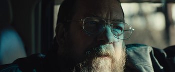Movie still from “Skin” (2018), directed by Guy Nattiv – A person with a beard wearing glasses; Close Up shot, Low angle