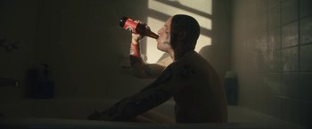 Movie still from “Skin” (2018), directed by Guy Nattiv – A tattooed man sitting in a bathtub drinking a beer; Medium shot, High angle