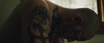 Movie still from “Skin” (2018), directed by Guy Nattiv – A man with tattoos on his arms and back; Close Up shot, Low angle
