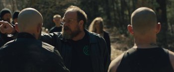 Movie still from “Skin” (2018), directed by Guy Nattiv – A man with a goatee and a beard wearing a black jacket; Medium shot, Over the shoulder angle