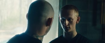 Movie still from “Skin” (2018), directed by Guy Nattiv – A man looking into a mirror while standing next to a wall; Close Up shot, Over the shoulder angle