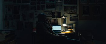 Movie still from “Skin” (2018), directed by Guy Nattiv – A man sitting in front of a laptop computer in a dark room; Medium shot, High angle