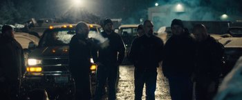 Movie still from “Skin” (2018), directed by Guy Nattiv – A group of people standing on a street at night; Medium shot, Over the shoulder angle