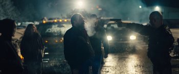 Movie still from “Skin” (2018), directed by Guy Nattiv – Two men standing in the rain with a gun pointed at them; Medium shot, Over the shoulder angle