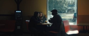 Movie still from “Skin” (2018), directed by Guy Nattiv – A group of people sitting at a table in front of a window; Medium shot, Over the shoulder angle