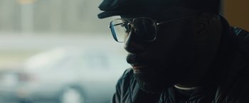 Movie still from “Skin” (2018), directed by Guy Nattiv – A person wearing glasses and a hat; Close Up shot, Low angle
