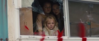 Movie still from “Skin” (2018), directed by Guy Nattiv – Three young girls looking out a broken window; Medium shot, Low angle