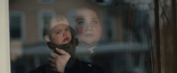Movie still from “Skin” (2018), directed by Guy Nattiv – A woman holding a baby in her arms through a window; Close Up shot, Over the shoulder angle