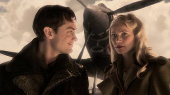 Movie still from “Sky Captain and the World of Tomorrow” (2004), directed by Kerry Conran – A man and a woman standing next to each other in front of an airplane; Close Up shot, Low angle