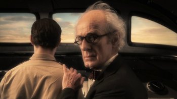 Movie still from “Sky Captain and the World of Tomorrow” (2004), directed by Kerry Conran – An older man in a suit and tie in front of a window; Close Up shot, Over the shoulder angle