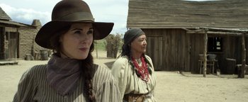 Movie still from “Godless” (2017), directed by Scott Frank – Two women dressed in old western clothing standing next to each other in front of a building; Close Up shot, Over the shoulder angle