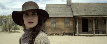 Movie still from “Godless” (2017), directed by Scott Frank – A woman wearing a hat standing in front of a house; Close Up shot, Low angle