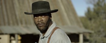 Movie still from “Godless” (2017), directed by Scott Frank – A man with a beard wearing a hat and suspenders; Close Up shot, Over the shoulder angle