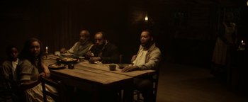 Movie still from “Godless” (2017), directed by Scott Frank – A group of men sitting at a wooden table; Wide shot, High angle