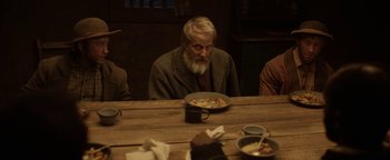 Movie still from “Godless” (2017), directed by Scott Frank – An old man sitting at a table with a bowl of food; Medium shot, Over the shoulder angle
