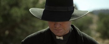 Movie still from “Godless” (2017), directed by Scott Frank – A man wearing a black hat and a black coat; Close Up shot, Low angle