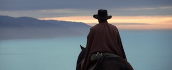 Movie still from “Godless” (2017), directed by Scott Frank – A man riding on the back of a black horse; Wide shot, Low angle