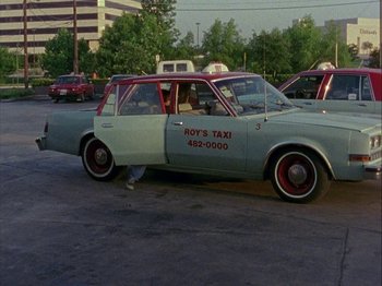 Movie still from “Slacker” (1990), directed by Richard Linklater – A man is standing next to a taxi cab; Wide shot, High angle