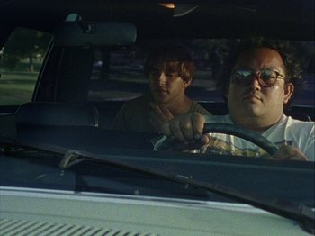 Movie still from “Slacker” (1990), directed by Richard Linklater – A man and a boy in the back seat of a car; Medium shot, Low angle