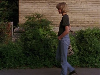 Movie still from “Slacker” (1990), directed by Richard Linklater – A man walking down the street with his hands in his pockets; Wide shot, Low angle