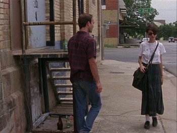 Movie still from “Slacker” (1990), directed by Richard Linklater – A man and a woman standing on the side of the street; Wide shot, Over the shoulder angle