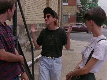 Movie still from “Slacker” (1990), directed by Richard Linklater – A group of people standing on the side of the street; Medium shot, Over the shoulder angle