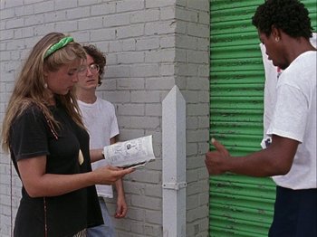 Movie still from “Slacker” (1990), directed by Richard Linklater – A group of people standing next to each other near a wall; Medium shot, Over the shoulder angle