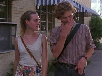 Movie still from “Slacker” (1990), directed by Richard Linklater – A man and a woman standing next to each other on the sidewalk; Medium shot, Low angle