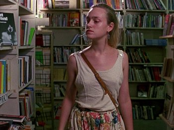 Movie still from “Slacker” (1990), directed by Richard Linklater – A woman standing in front of bookshelves in a library; Medium shot, Low angle